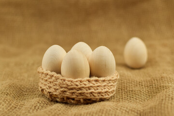 Decorative wooden Easter eggs in a wicker basket. Eastern eggs closeup on a vintage background.
