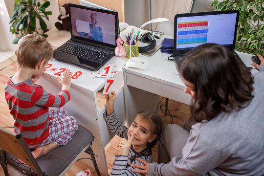 Distant Education At Home, Children Doing Homework And Mother Working And Help Them. Elementary School Kids During Online Class With Parent Working Remotely In One Room, Self-isolation, Quarantine