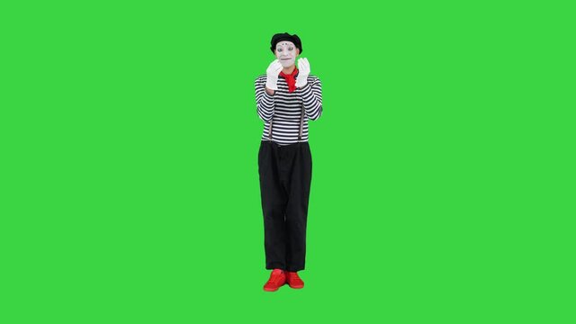 Mime in striped sweater, white gloves sending his heart to camera on a Green Screen, Chroma Key.