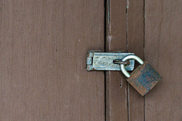 Old rusty padlock locked old wood brown door. Home security.