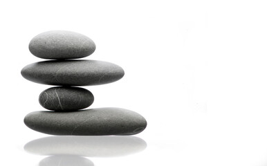 Balanced pile of four grey stones, reflex on white table, equilibrium concept
