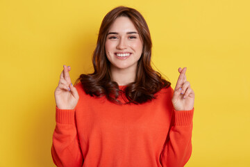 Happy dark haired female believing dreams come true. Hopeful woman feels lucky, crosses fingers,...