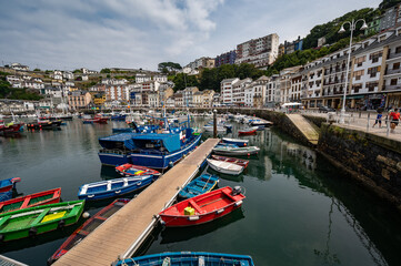 Fototapeta premium The Austurian port village of Luarca showing boats in harbor and tourists on promenade