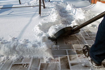 A man clears snow from a path after a blizzard using a snow shovel.