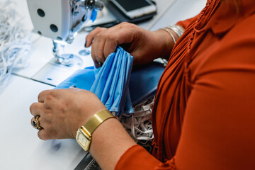 Closeup image of a woman's hands working on a sewing machine in a mask factory