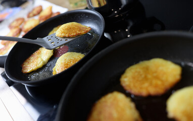 Potato latkes are cooked in skillet in kitchen closeup
