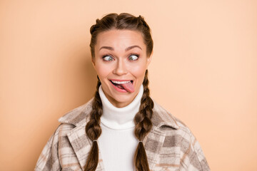 Portrait of nice hairstyle childish person squinting eyes tongue out wear plaid isolated on beige...