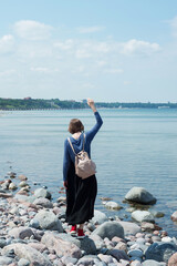 Woman with backpack on stones near the seashore