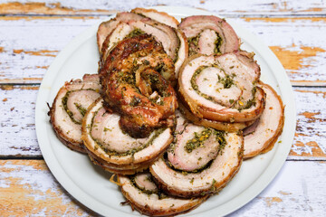 Well grilled porchetta sliced into rounds in a dish and ready to serve