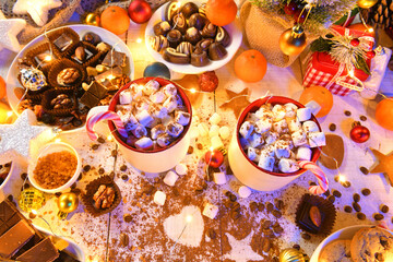 Naklejka premium sweet food top view background for merry christmas or new year holiday decoration with night illumination - chocolate candies, tangerines, cookies, marshmallow and cocoa latte on white wood