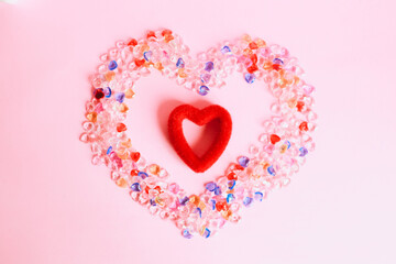 Colorful heart shape marbles with red heart shape in the middle isolated on pink background
