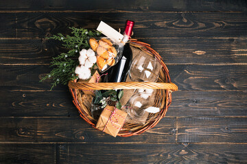 Bottles of red wine in Christmas basket. Mulled wine with gift boxes, cookies and fir-tree...