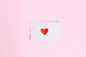 Top view of mini red heart shape on envelope with pink background
