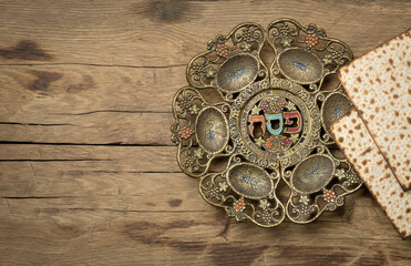 Jewish Passover holiday. Matzot and vintage traditional Pesah plate with text in hebrew: Passover, horseradish, celery, egg, bone, maror, charoset.