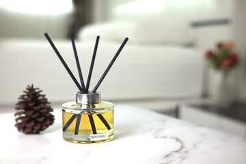 luxury aromatic scent of reed diffuser glass bottle is used as room freshener on the marble table in the bedroom creat relax ambient with background of light from window and white bed in the morning