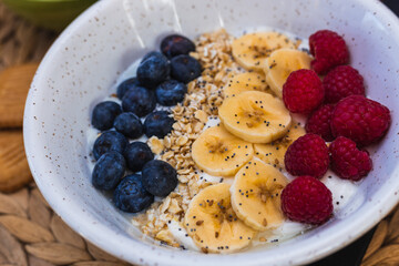 Close up picture of a healthy breakfast with bananas, blueberry's. raspberry's,oat and yogurt