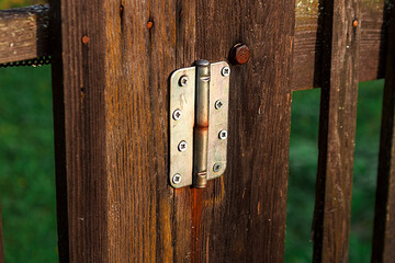 Hinge for canopy of gate made of brown boards on fence