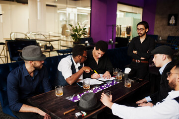 Group of handsome retro well-dressed man gangsters spend time at club. Multiethnic male bachelor mafia party in restaurant.