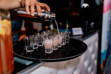 the bartender pours drinks into glasses