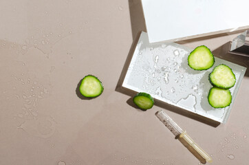 Top view of white stages, slices of cucumber and dropper on the wet beige surface.Empty space.Beauty ingredients