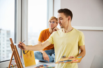 Handsome man painting picture and spending time with boyfriend