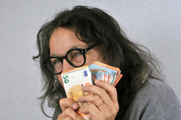 Femme radine tenant des billets de banque en euro en main