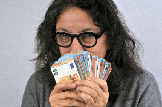 Femme radine tenant des billets de banque en euro en main