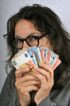 Femme radine tenant des billets de banque en euro en main
