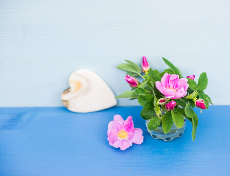 Tiny bouquet of roses with Heart of marble on an blue wooden table. Valentine background.
