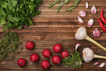 Fototapeta na wymiar Radish, garlic, parsley rosemary and micro green are laid out on a wooden kitchen table
