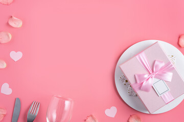 Plate with gift and rose petals for Valentine's Day special meal concept.
