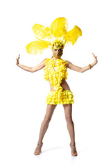 Face mask. Beautiful young woman in carnival, stylish masquerade costume with feathers dancing on white studio background. Concept of holidays celebration, festive time, dance, party, having fun.