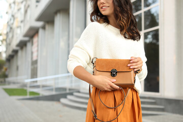 Young woman with stylish brown bag on city street, closeup