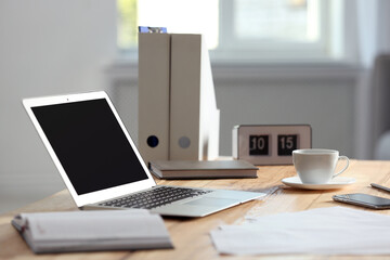 Modern laptop and supplies on table in office