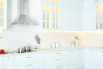 Fototapeta na wymiar Blurred view of modern kitchen interior with white furniture