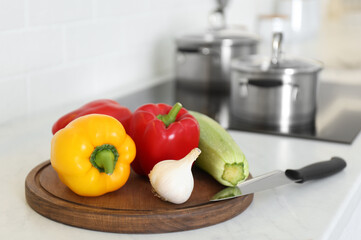 Fresh vegetables and knife on white counter in kitchen
