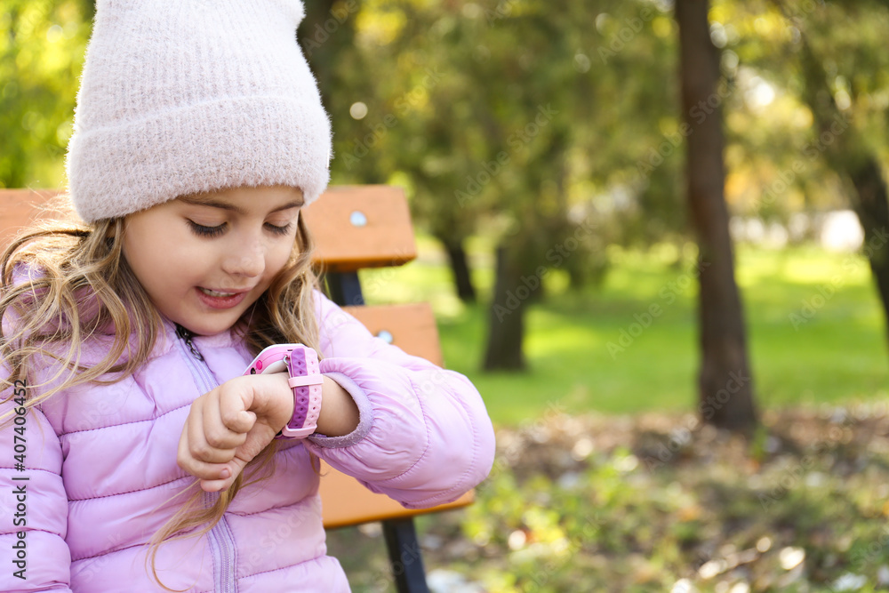 Wall mural little girl using modern smart watch outdoors