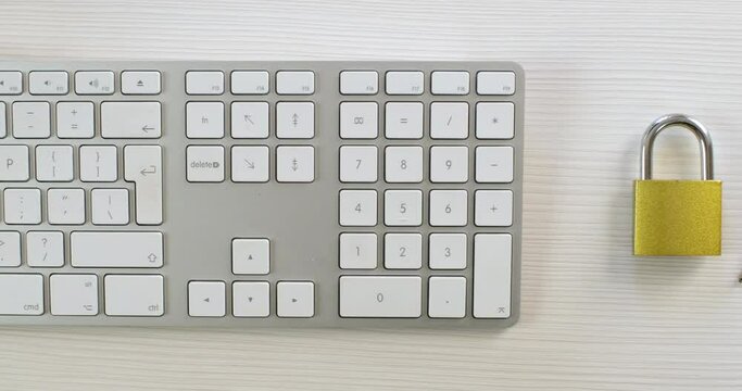 A man types an access password on the keyboard, with a lock and a bunch of keys next to it, close up. Personal data enhanced protection.