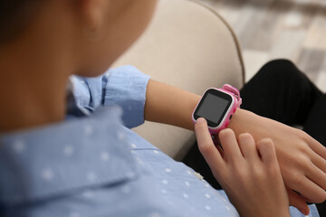 Girl using stylish smart watch on sofa indoors, closeup