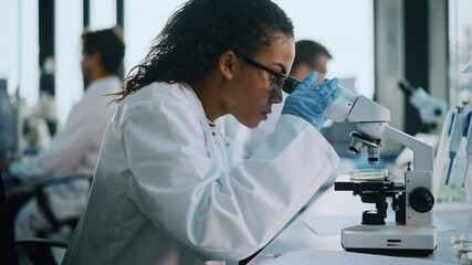 Medical Science Laboratory: Beautiful Black Scientist Looking Under Microscope, writes down Analysis Data - Powered by Adobe
