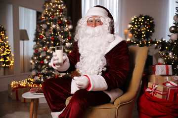 Fototapeta na wymiar Santa Claus with glass of milk and cookie in room decorated for Christmas