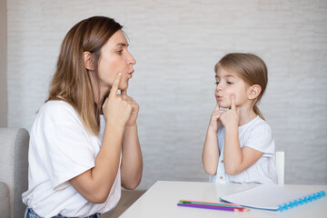Cute little girl with speech therapist.Young woman teacher and child on private lesson.