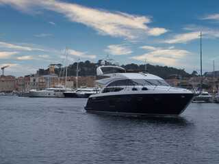 Saint Tropez, France - Mai 06th 2018: A german photographer exploring the harbor with its expensive yachts with the center of the village in the background at a cloudy day in spring. 