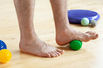 man doing flatfoot correction gymnastic exercise using massage roller at home