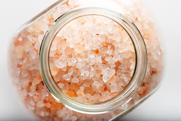 Fototapeta na wymiar Big Crystals of pink Himalayan salt in jar. White background. Top view. Close up.