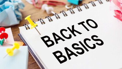 BACK TO BASIC - text on a notepad with wrinkled paper and paper needles on wooden background