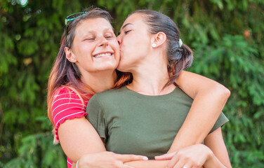 couple of friends kiss each other hugging each other at the park