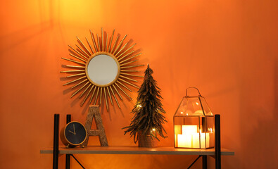Shelf with Christmas decor near orange wall. Interior design
