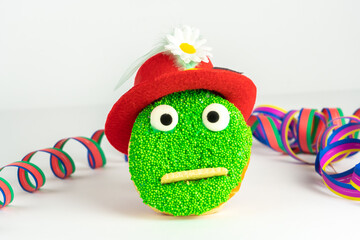 Funny green face cake with red hat and streamer, white background