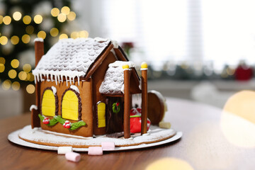 Fototapeta na wymiar Beautiful gingerbread house decorated with icing on wooden table indoors, space for text